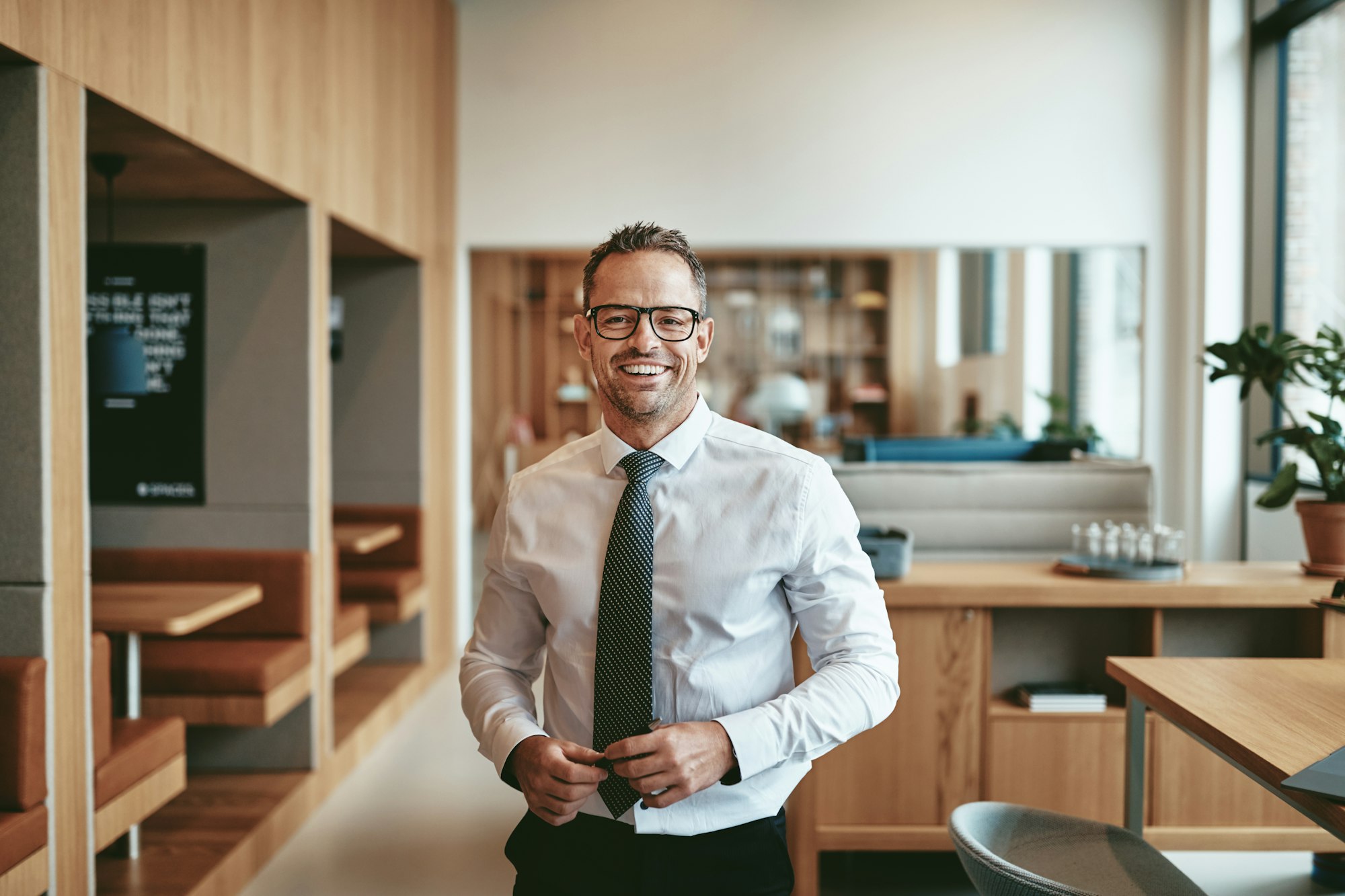 Smiling mature businessman standing alone in an office cafeteria